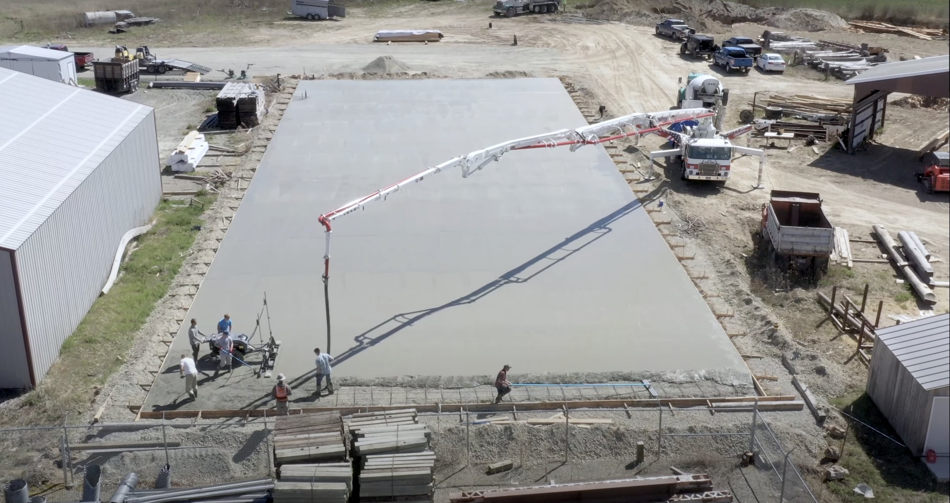 Aerial view of large-scale concrete slab installation with concrete pump truck and professional crew